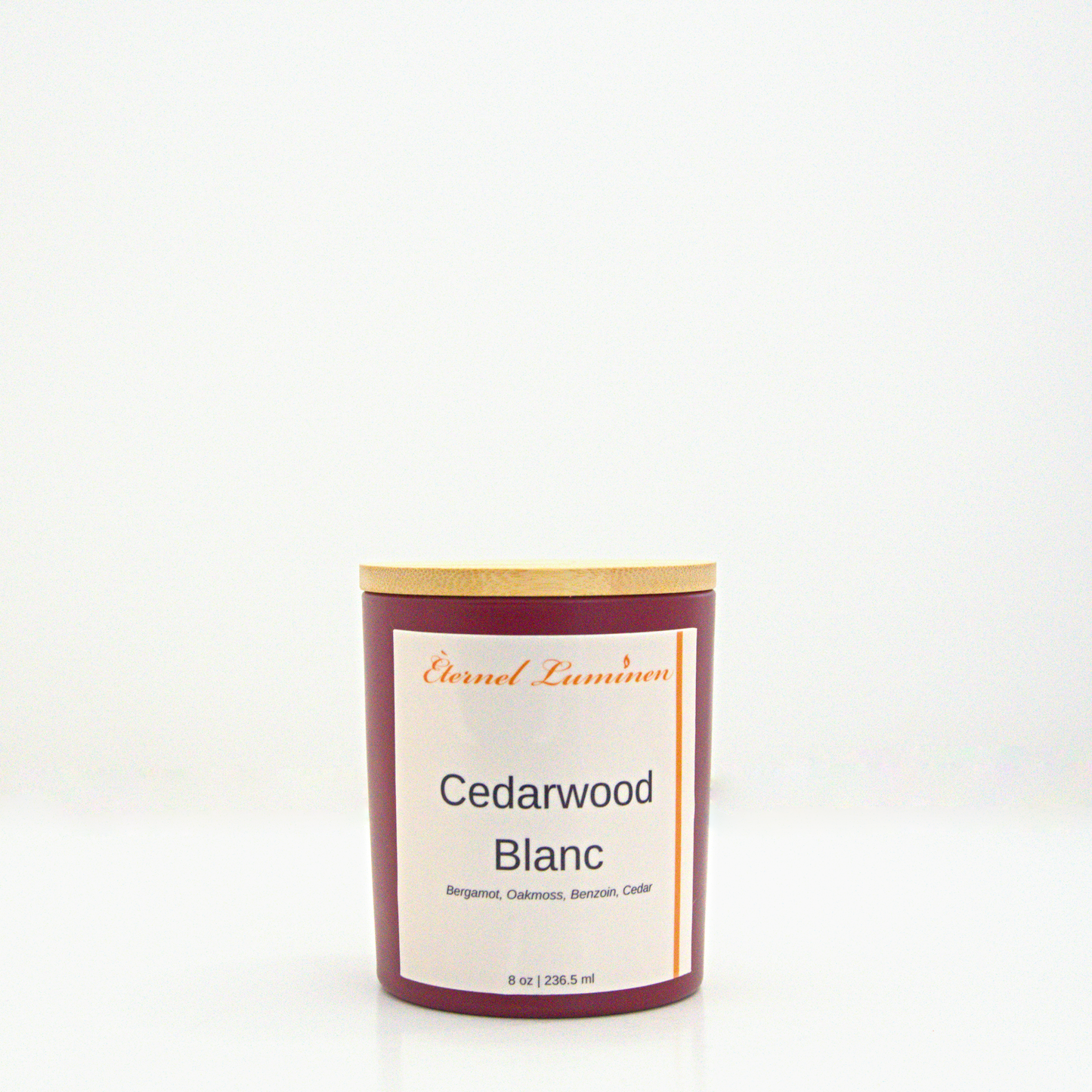 A 8oz frosted Cedarwood Blanc candle with a wooden lid sitting against a white background