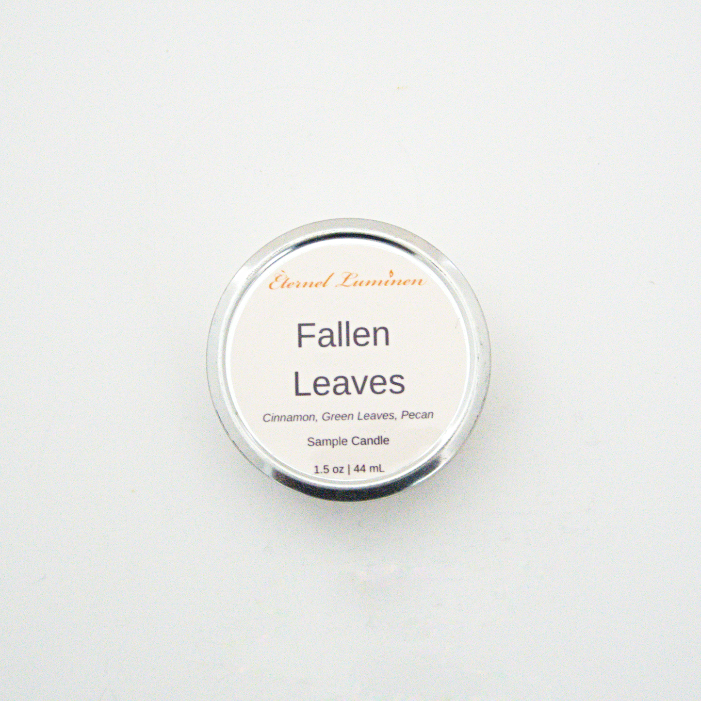 A 1.5oz Fallen Leaves sample candle in a tin jar sitting against a white background made by Eternel Luminen