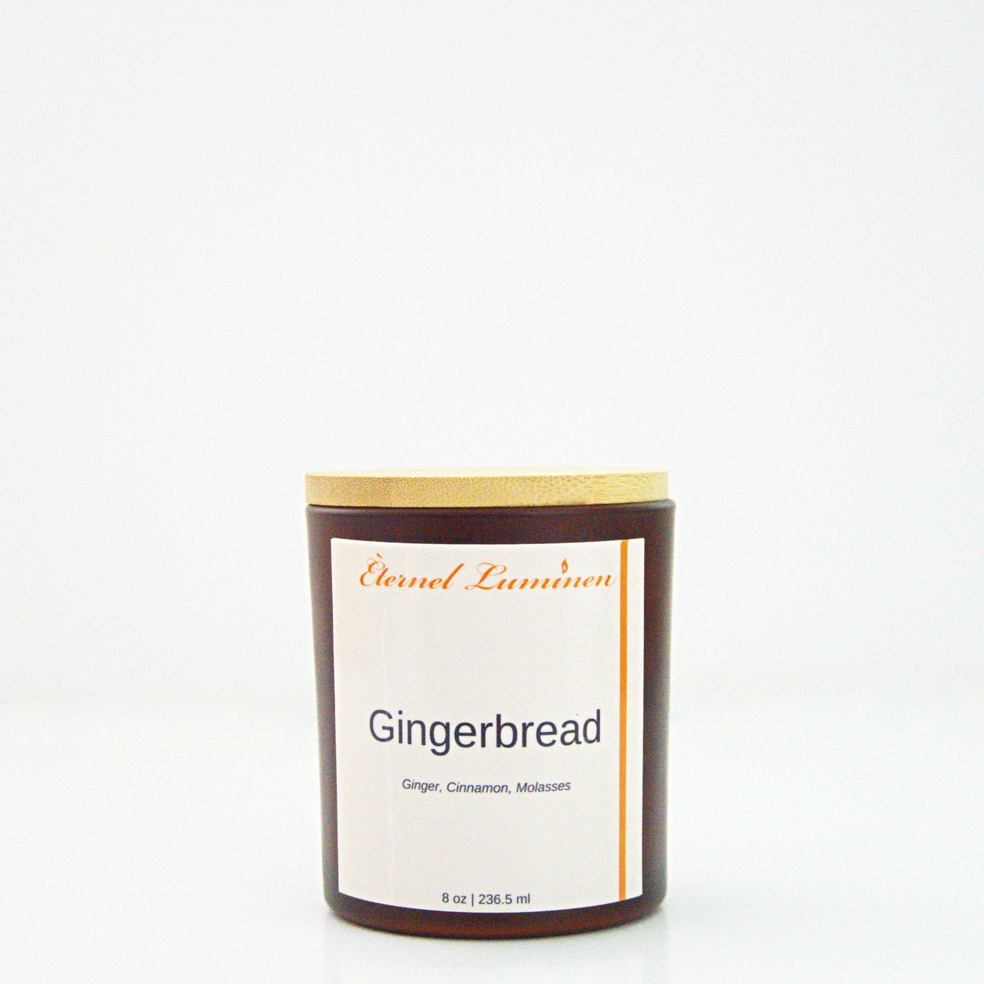 A 8 oz Gingerbread frosted candle with a wooden lid sitting against a white background made by Eternel Luminen.