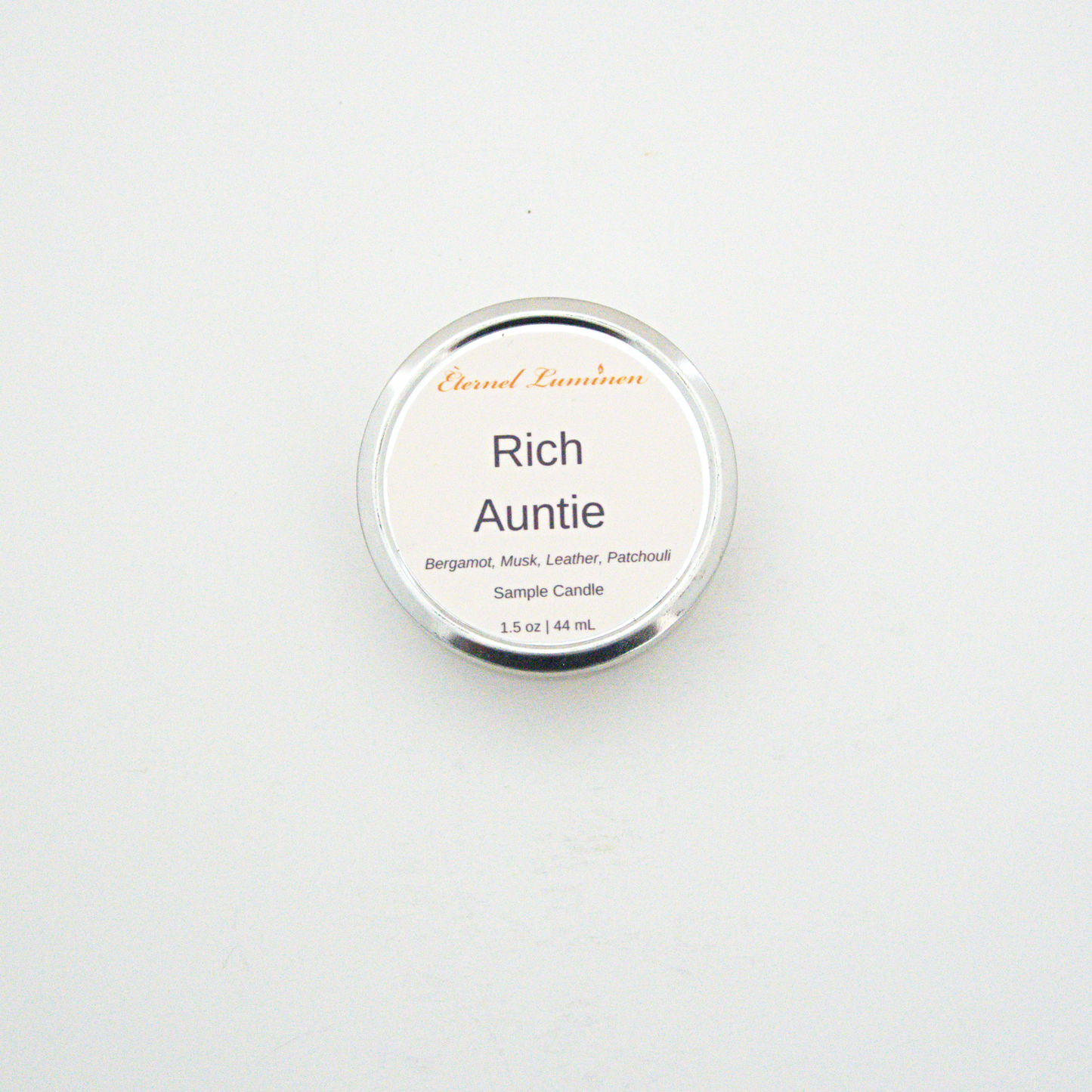 A 1.5oz Rich Auntie sample candle in a tin jar sitting against a white background made by Eternel Luminen