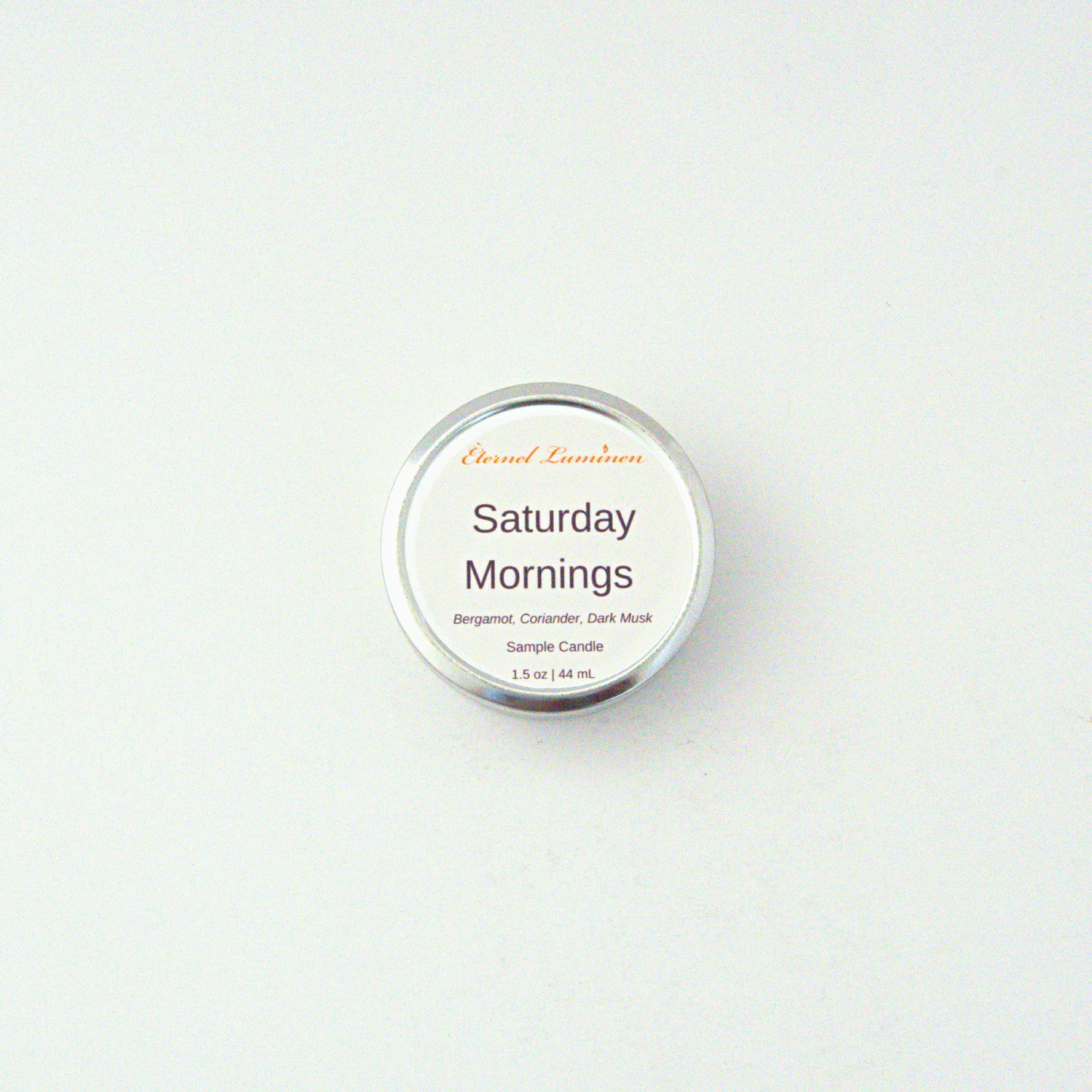 A 1.5oz Saturday Mornings sample candle in a tin jar sitting against a white background made by Eternel Luminen
