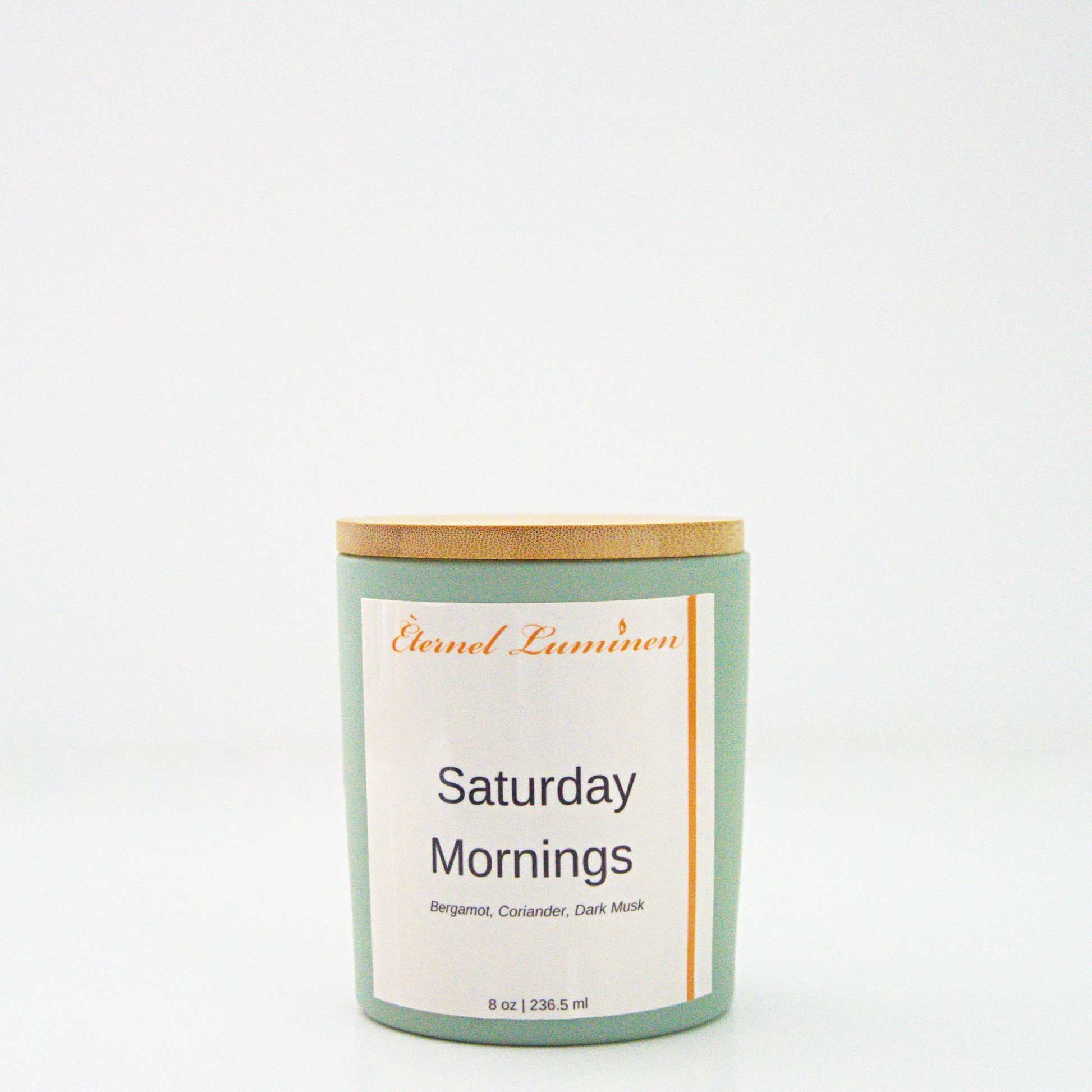 A 8 oz frosted Saturday Mornings candle with a wooden lid sitting against a white background made by Eternel Luminen.