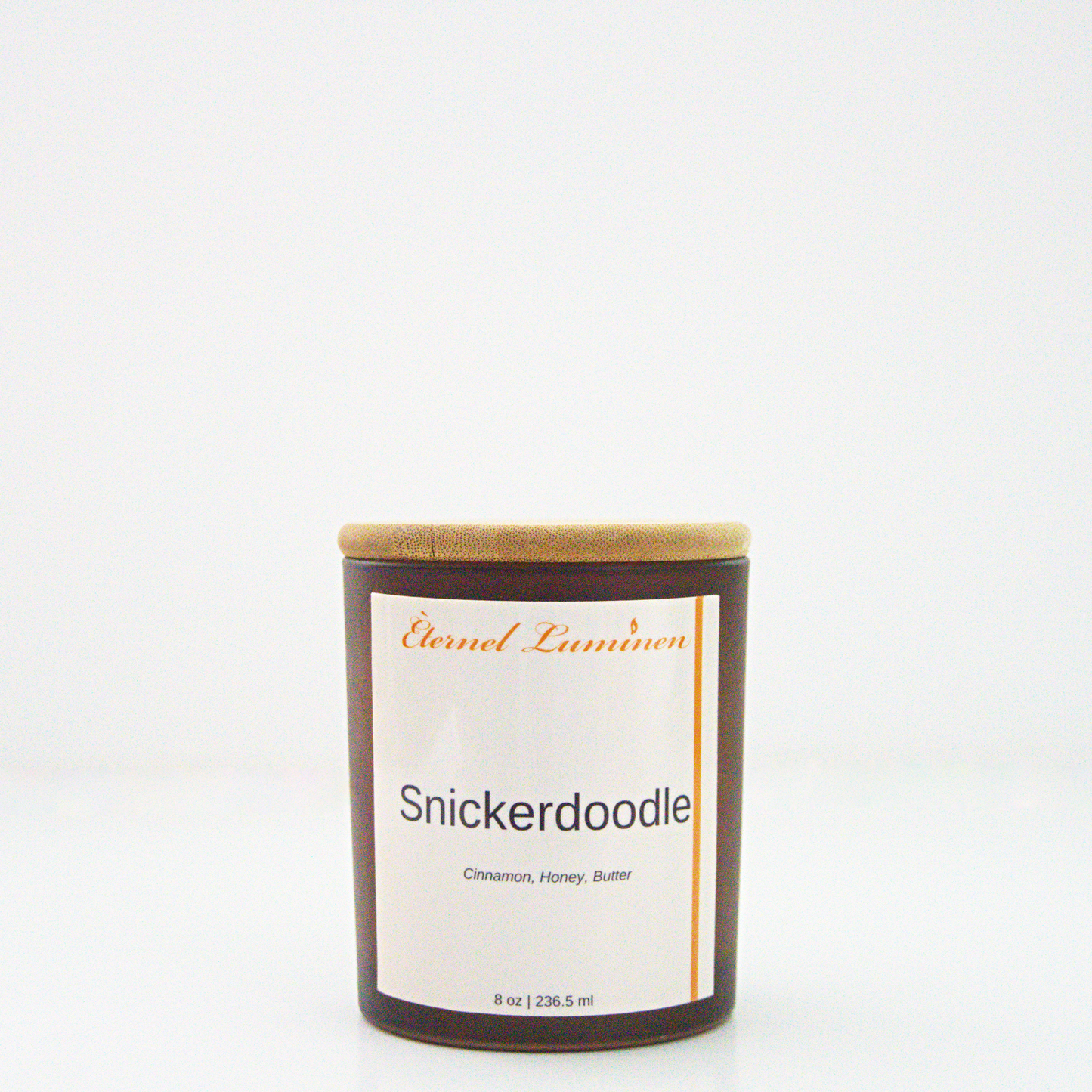 A 8oz snickerdoodle frosted candle with a wooden lid sitting against a white background made by Eternel Luminen.