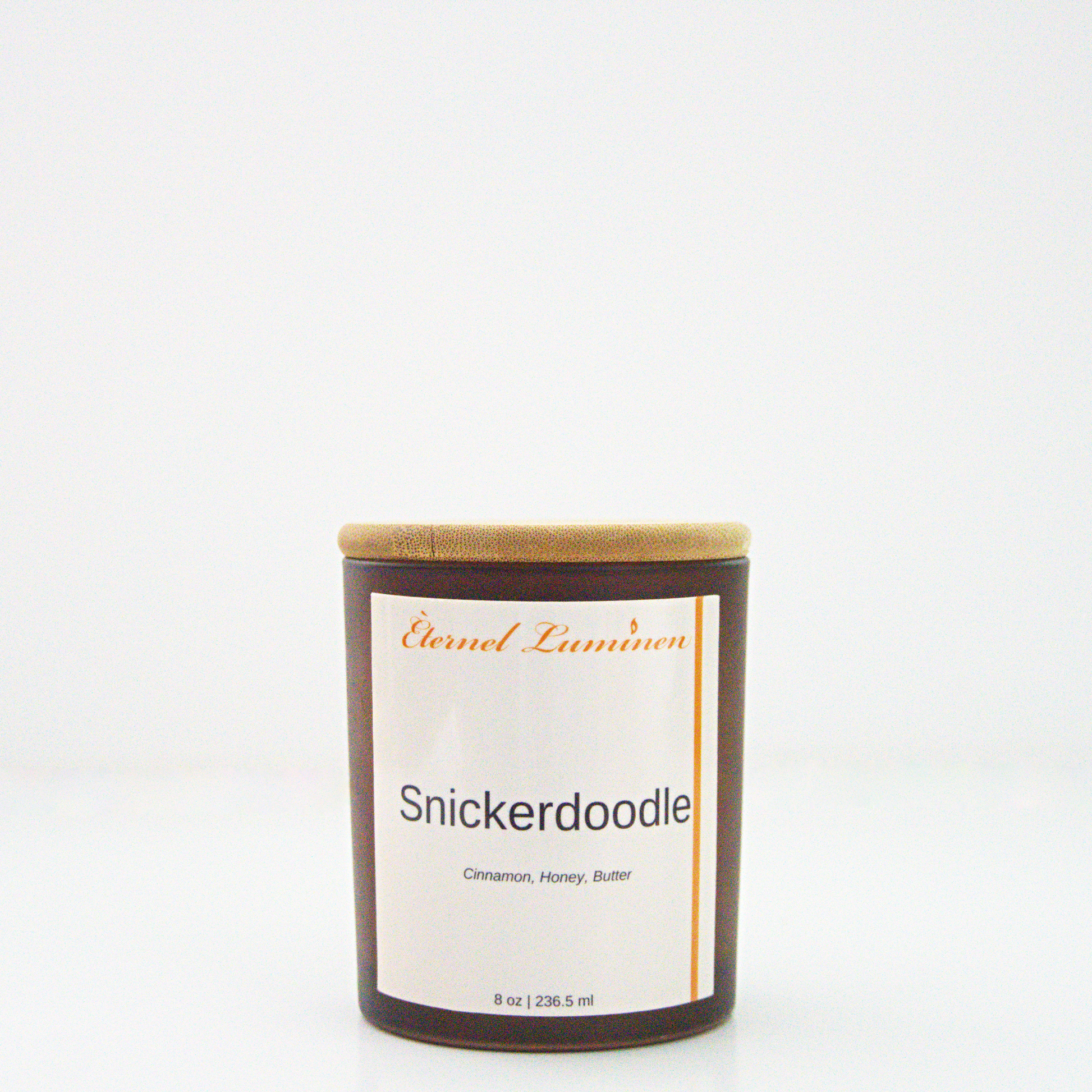 A 8oz snickerdoodle frosted candle with a wooden lid sitting against a white background made by Eternel Luminen.