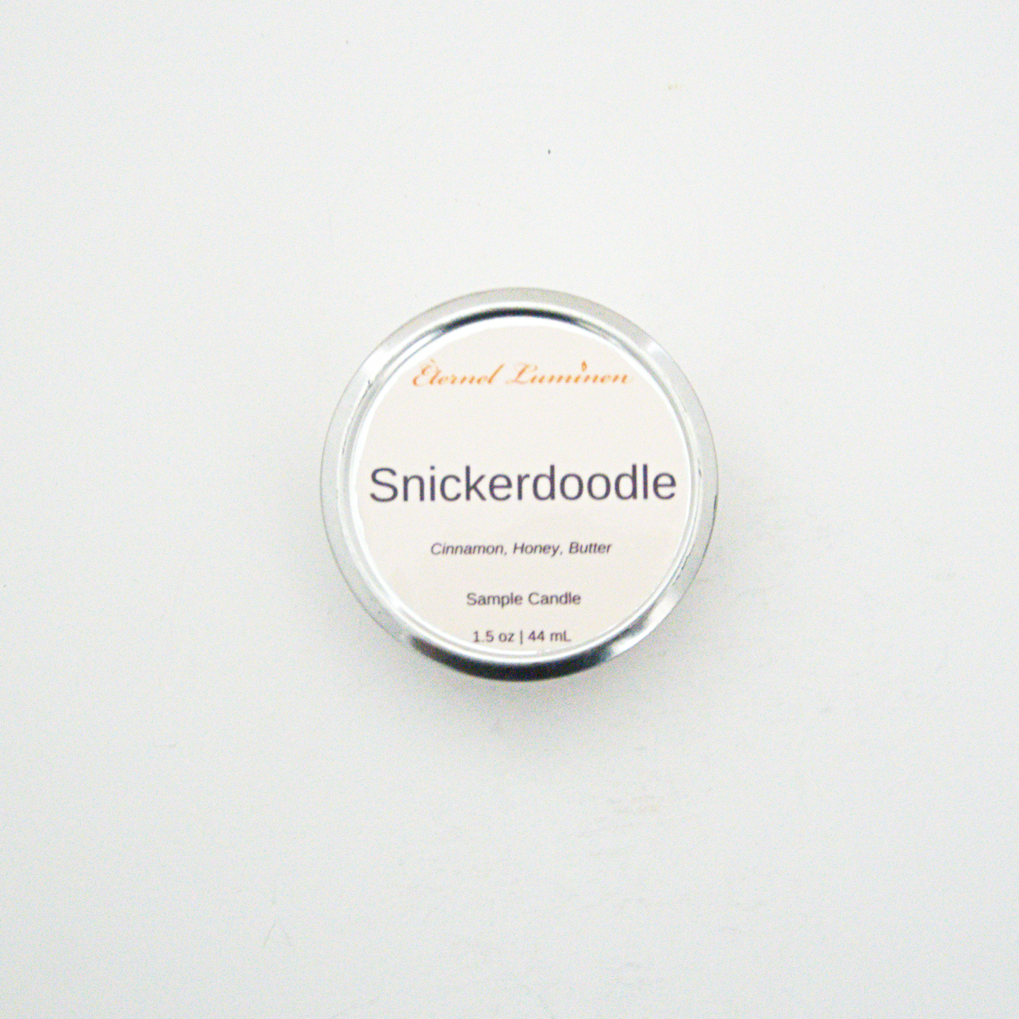 A 1.5oz Snickerdoodle sample candle in a tin jar sitting against a white background made by Eternel Luminen