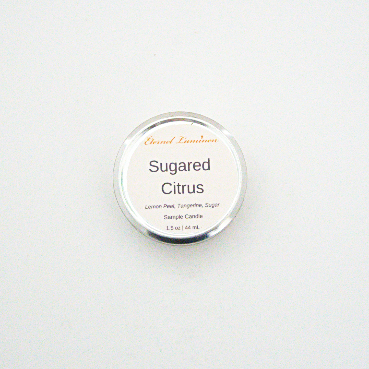 A 1.5oz Sugared Citrus sample candle in a tin jar sitting against a white background made by Eternel Luminen.