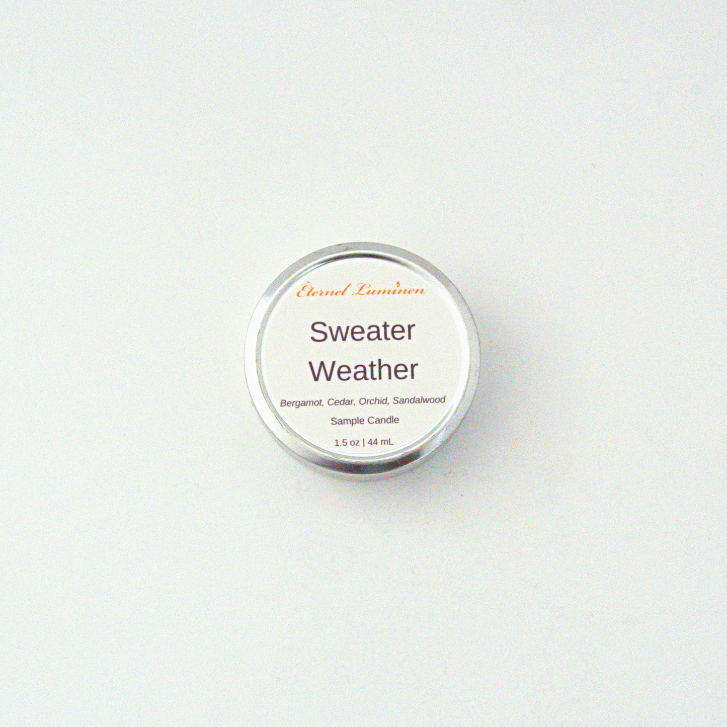 A 1.5oz Sweater Weather sample candle in a tin jar sitting against a white background made by Eternel Luminen