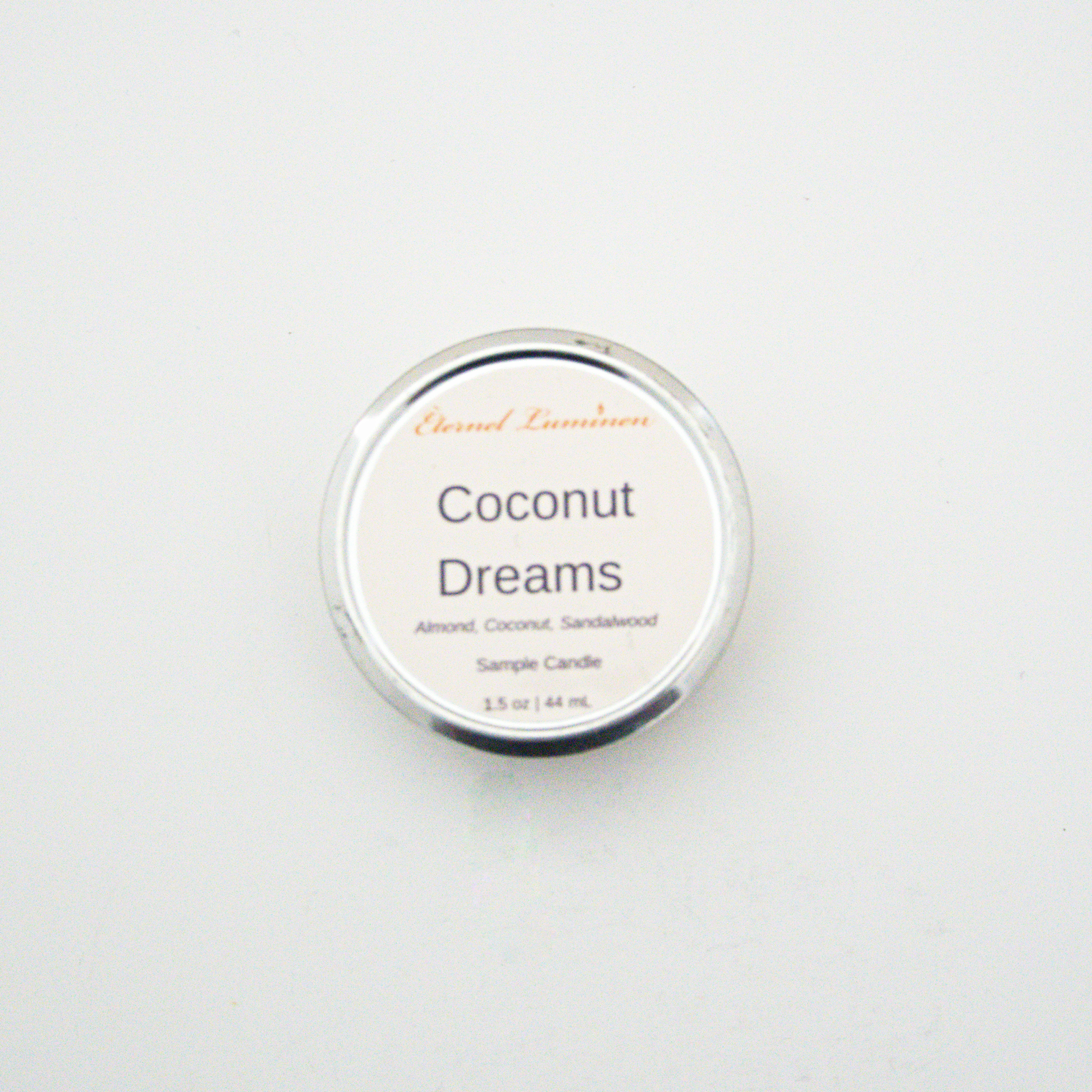 A 1.5oz Coconut Dreams sample candle in a tin jar sitting against a white background made by Eternel Luminen