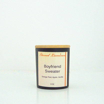 A 8 oz frosted Boyfriend Sweater candle with a wooden lid sitting against a white background made by Eternel Luminen.