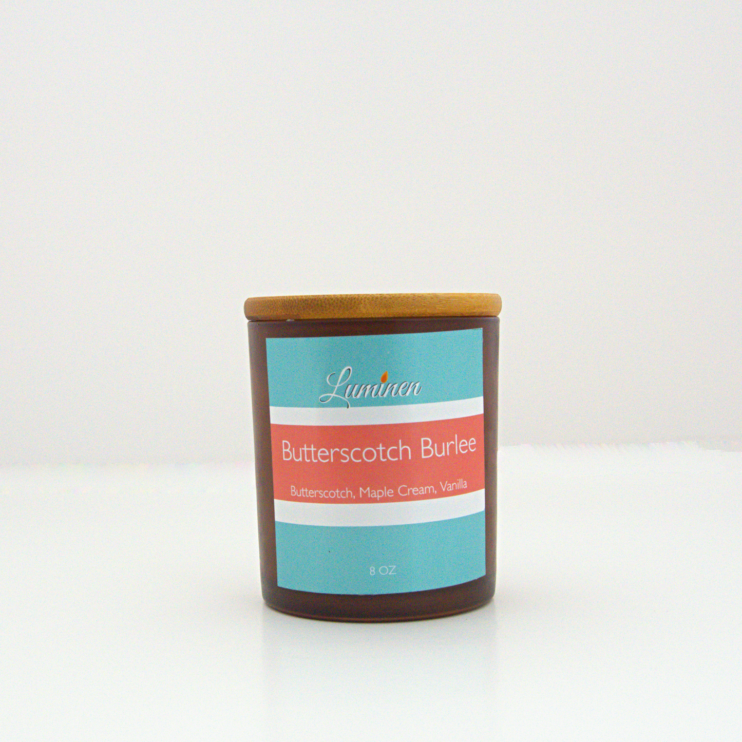 A 8oz frosted Butterscotch Burlee candle with a wooden lid sitting against a white background made by Eternel Luminen.