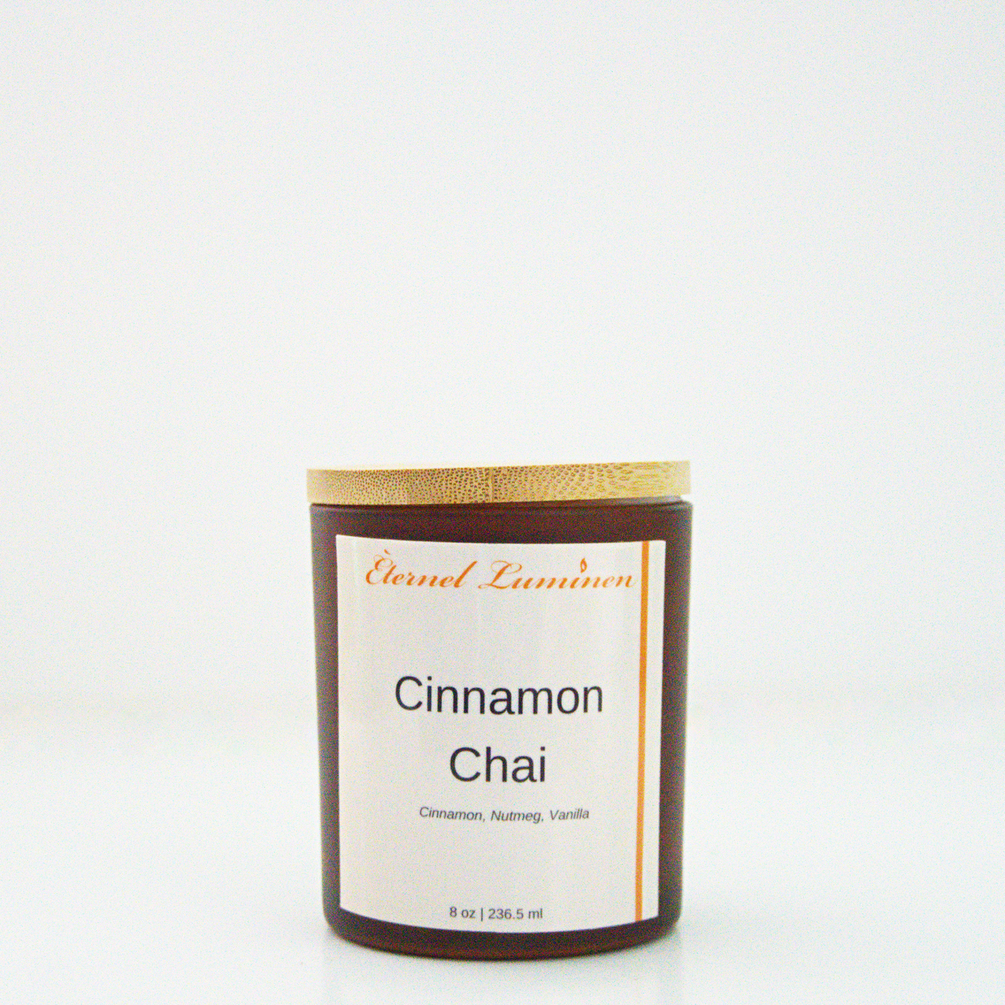 A 8 oz frosted Cinnamon Chai candle with a wooden lid sitting against a white background