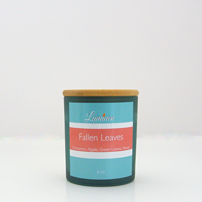 A 8oz fallen leaves frosted candle with a wooden lid sitting against a white background made by Eternel Luminen.