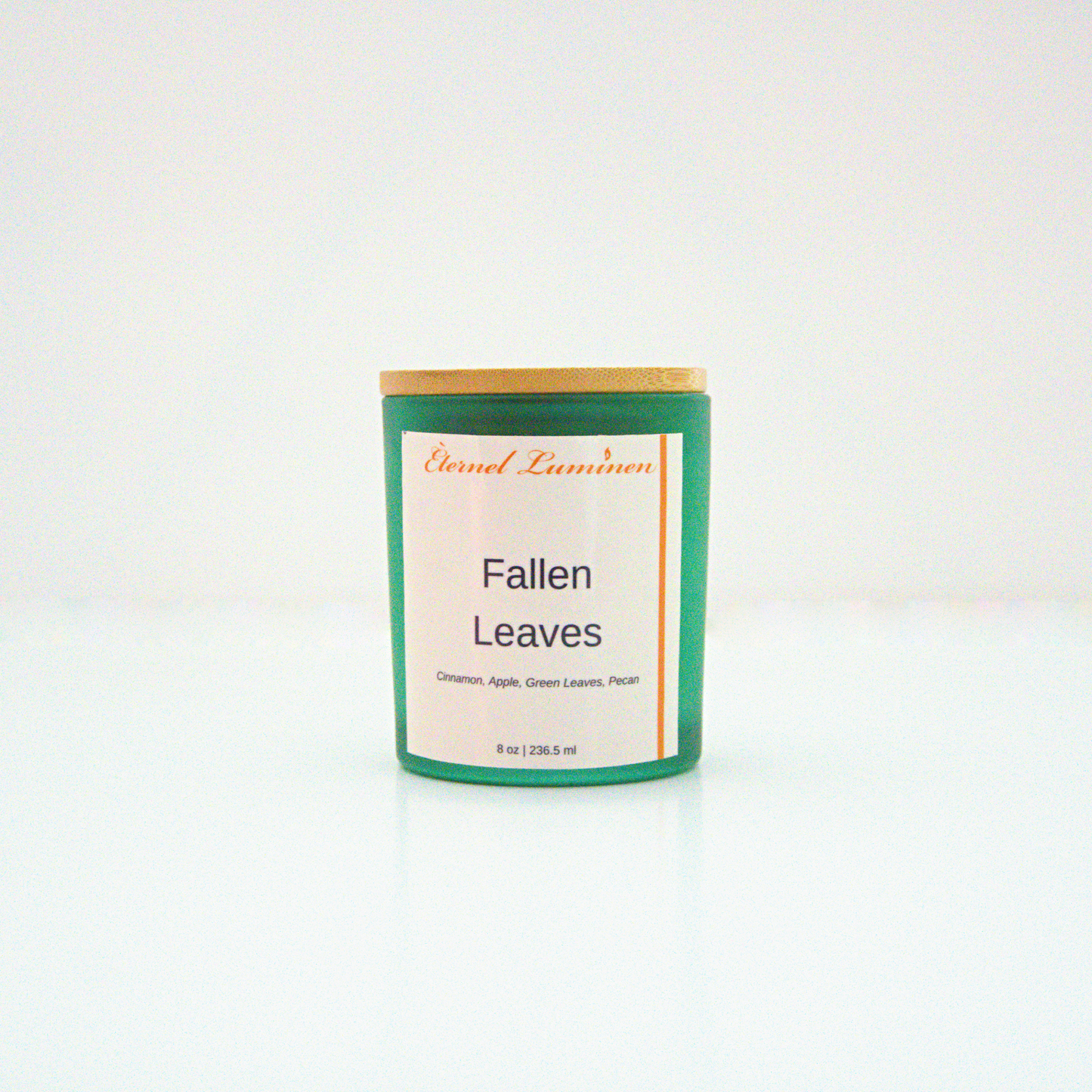 A 8 oz frosted Fallen Leaves candle with a wooden lid sitting against a white background made by Eternel Luminen.