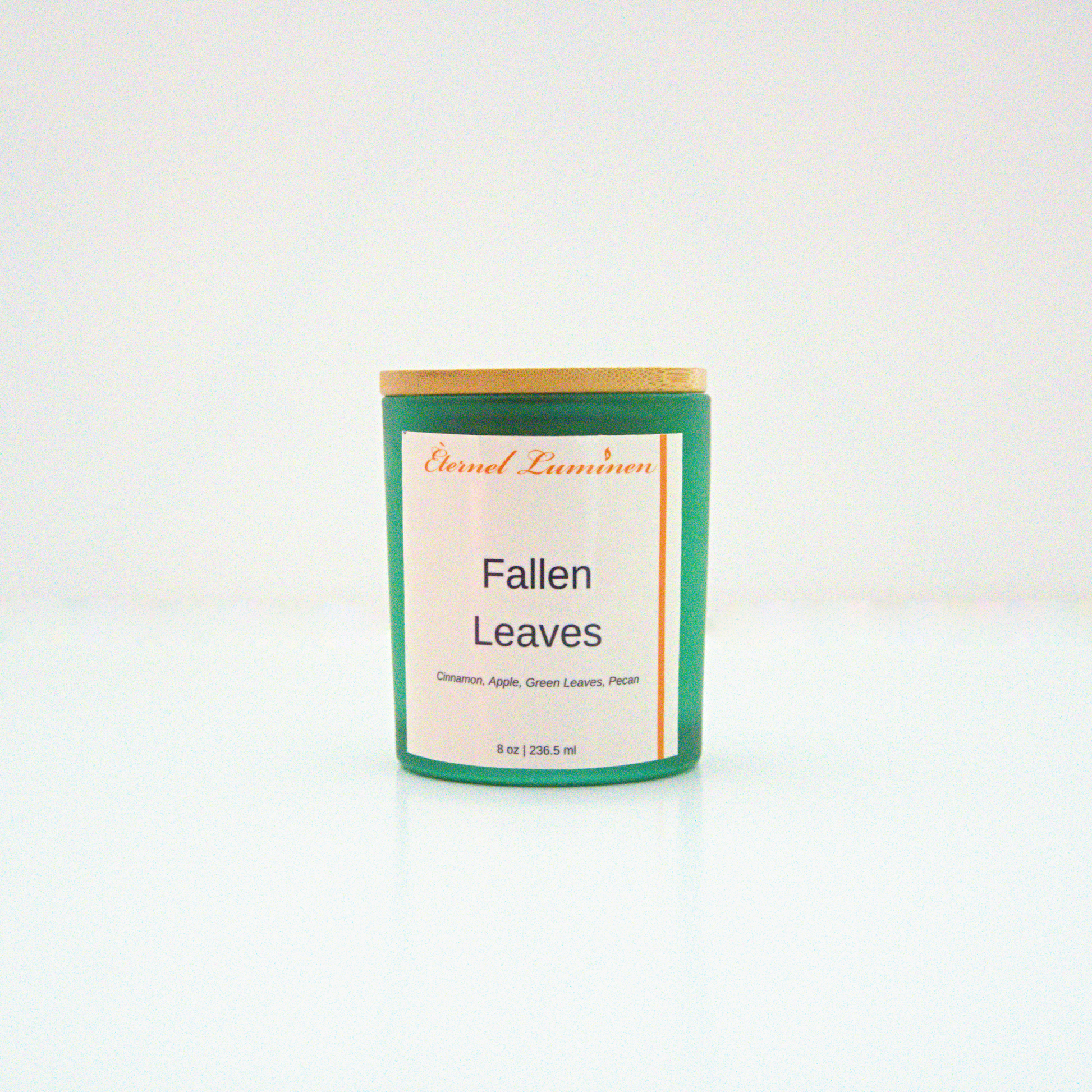 A 8 oz frosted Fallen Leaves candle with a wooden lid sitting against a white background made by Eternel Luminen.