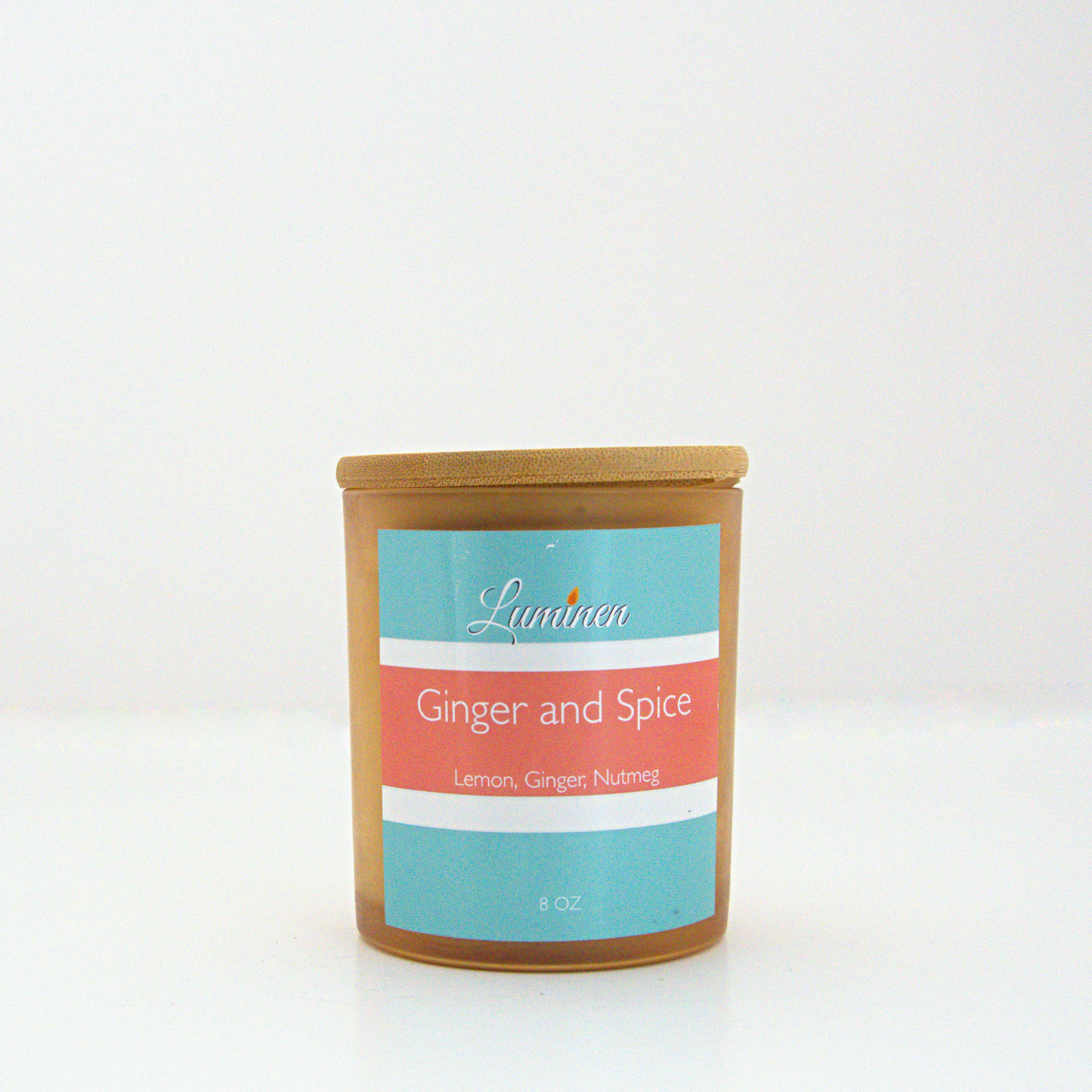 A 8 oz Ginger & Spice frosted candle with a wooden lid sitting against a white background made by Eternel Luminen.