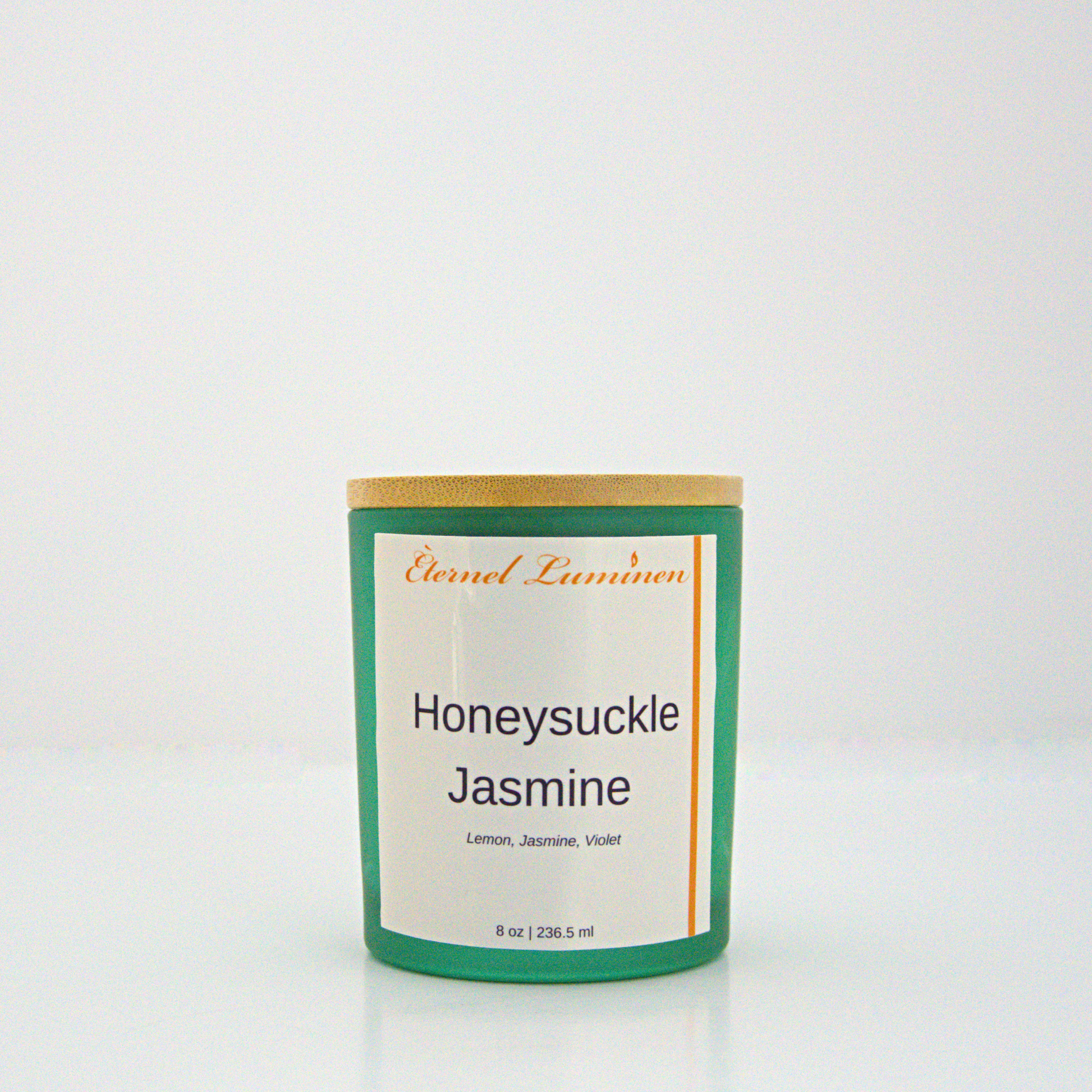 A 8 oz Honeysuckle Jasmine frosted candle with a wooden lid sitting against a white background made by Eternel Luminen.