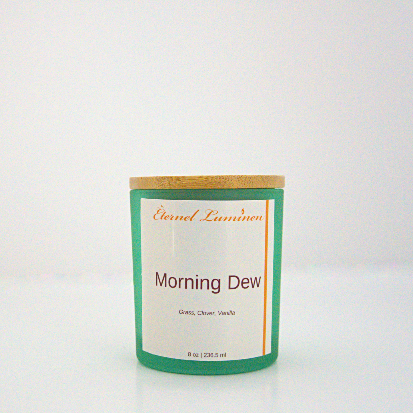 A 8 oz frosted Morning Dew candle with a wooden lid sitting against a white background made by Eternel Luminen.