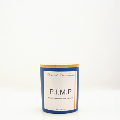 A 8 oz P.I.M.P frosted candle with a wooden lid sitting against a white background