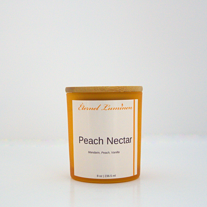 A 8 oz Peach Nectar frosted candle with a wooden lid sitting against a white background made by Eternel Luminen.