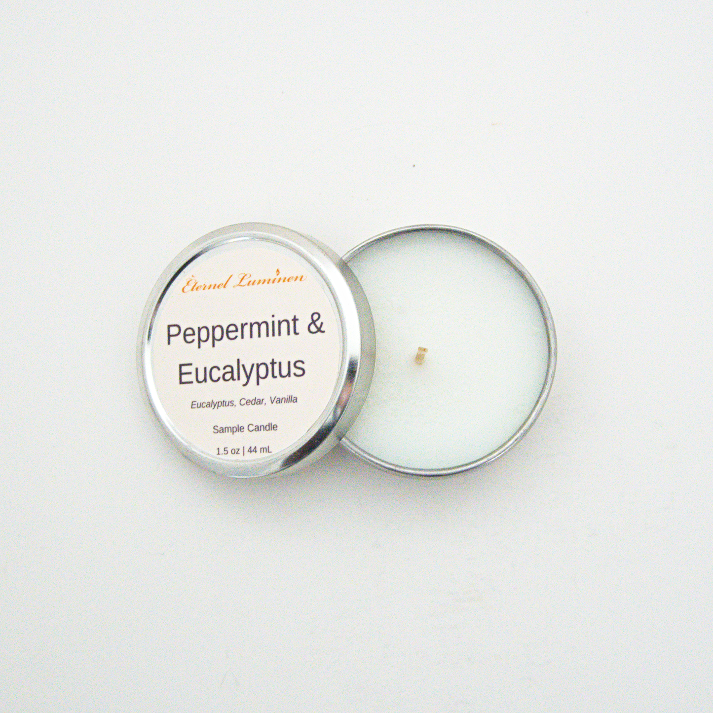A 1.5oz Peppermint & Eucalyptus sample candle in a tin jar with the lid off sitting against a white background made by Eternel Luminen.