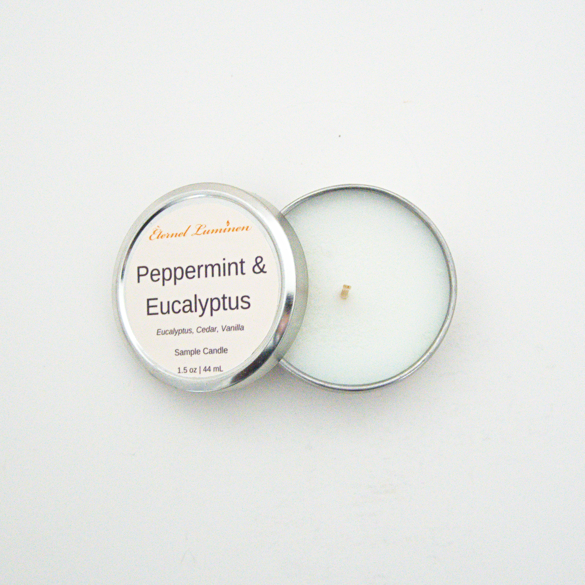 A 1.5oz Peppermint & Eucalyptus sample candle in a tin jar with the lid off sitting against a white background made by Eternel Luminen.