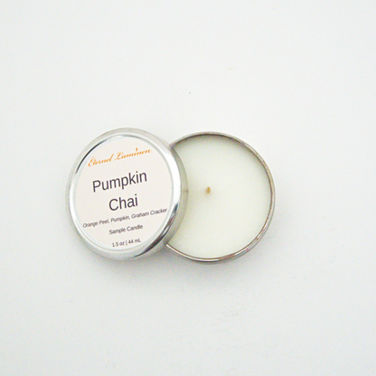 A 1.5oz Pumpkin Chai sample candle in a tin jar with the lid off sitting against a white background made by Eternel Luminen.