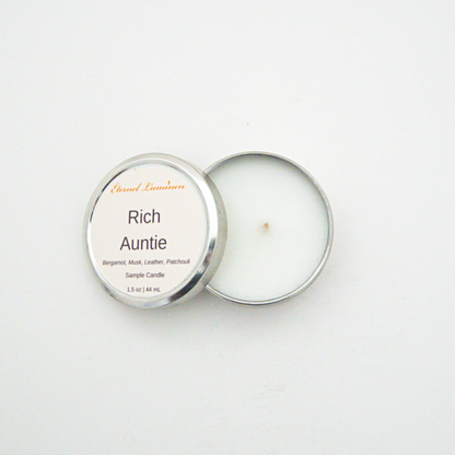 A 1.5oz Rich Auntie sample candle in a tin jar with the lid off sitting against a white background made by Eternel Luminen.