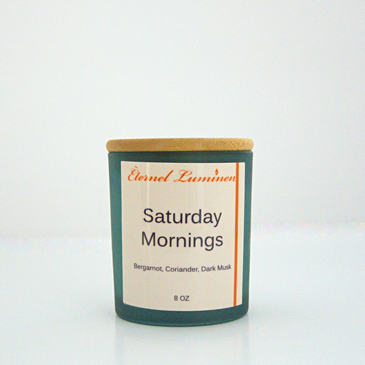 A 8 oz frosted Saturday Mornings candle with a wooden lid sitting against a white background made by Eternel Luminen.