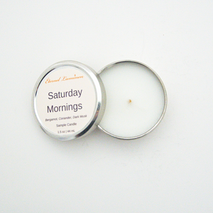 A 1.5oz Saturday Mornings sample candle in a tin jar with the lid off sitting against a white background made by Eternel Luminen.