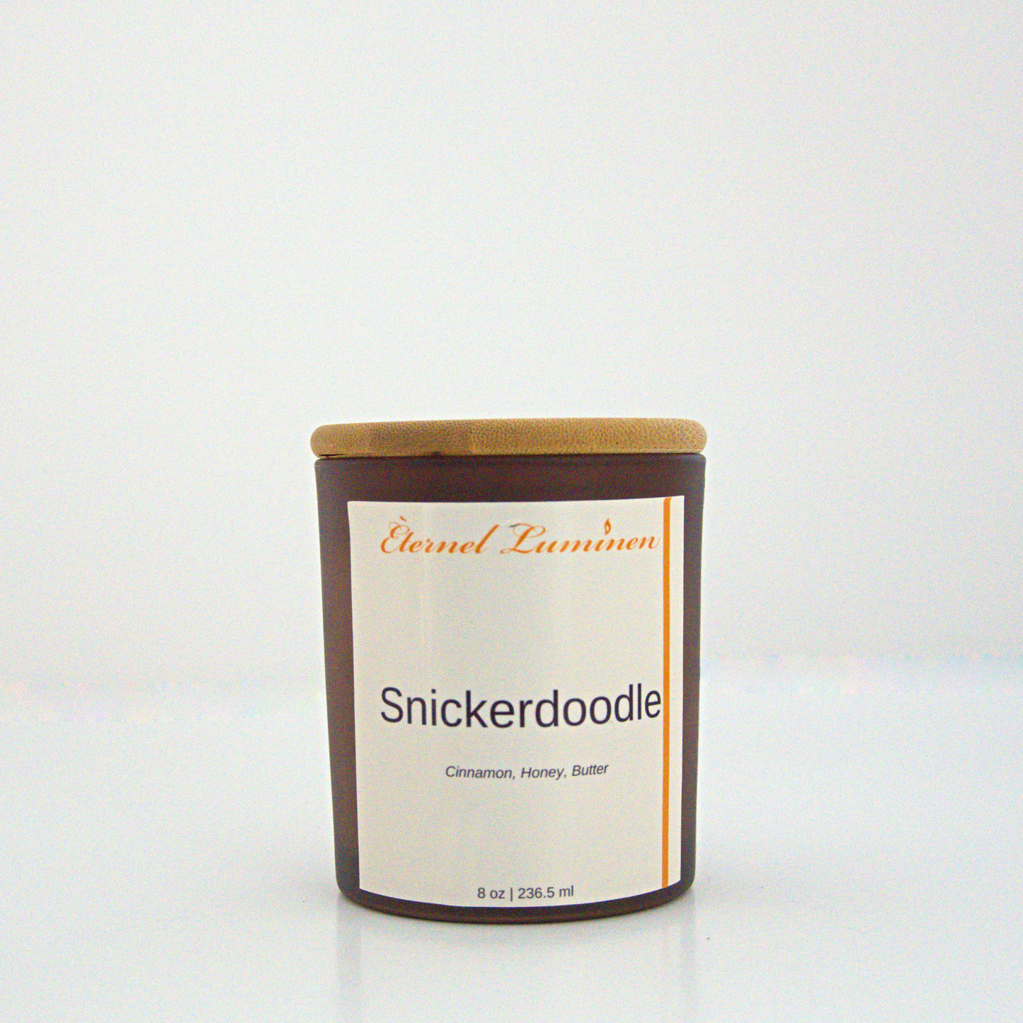 A 8oz snickerdoodle frosted candle with a wooden lid sitting against a white background made by Eternel Luminen.