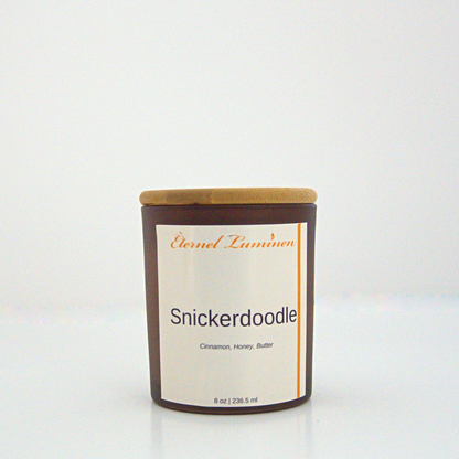 A 8oz snickerdoodle frosted candle with a wooden lid sitting against a white background made by Eternel Luminen.