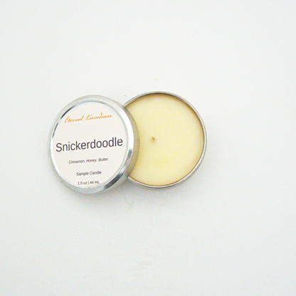 A 1.5oz Snickerdoodle sample candle in a tin jar with the lid off sitting against a white background made by Eternel Luminen.