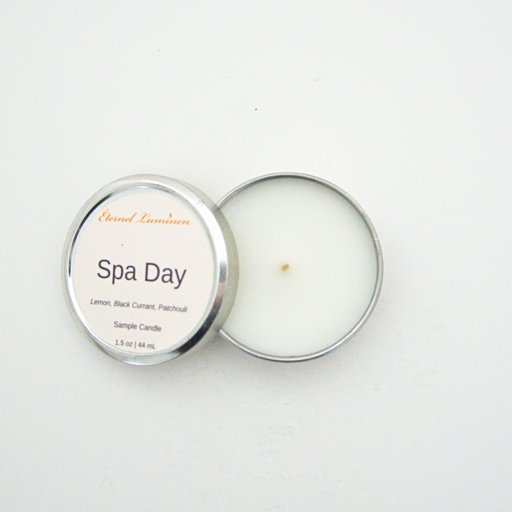 A 1.5oz Spa Day sample candle in a tin jar with the lid off sitting against a white background made by Eternel Luminen.