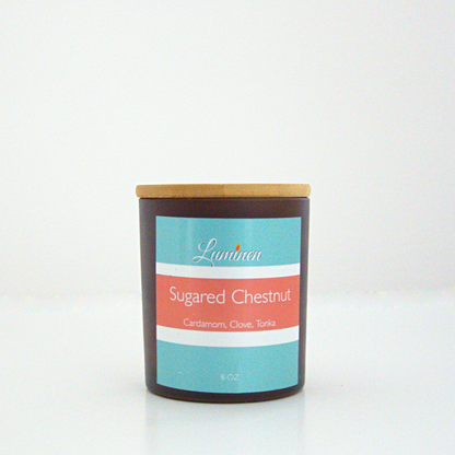 A 8oz Sugared Chestnut frosted candle with a wooden lid sitting against a white background made by Eternel Luminen.