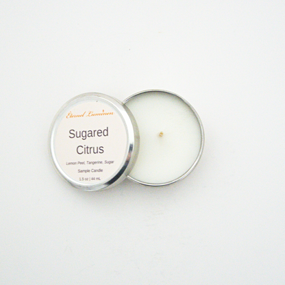 A 1.5oz Sugared Citrus sample candle in a tin jar with the lid off sitting against a white background made by Eternel Luminen.