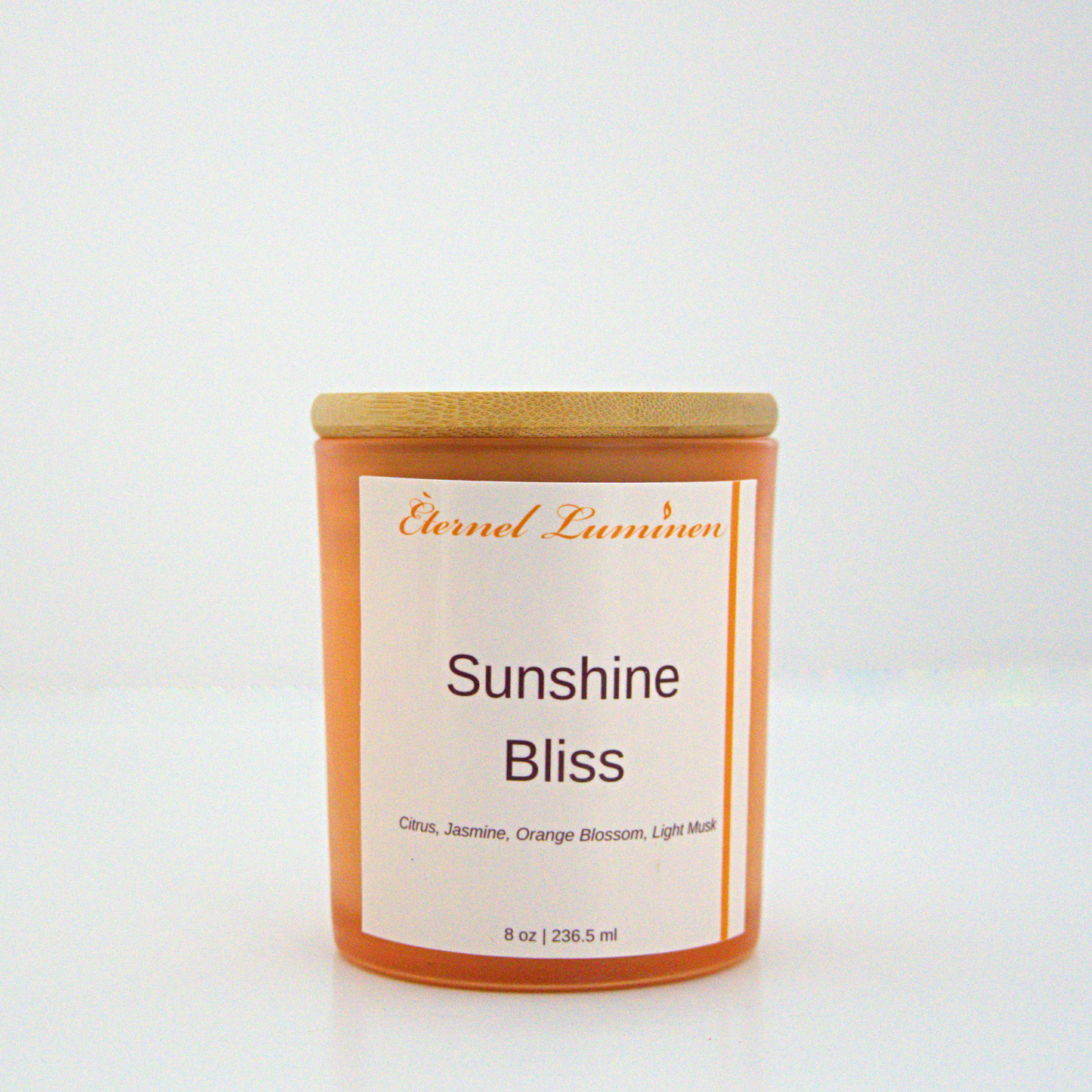 A 8 oz frosted Sunshine Bliss candle with a wooden lid sitting against a white background made by Eternel Luminen.