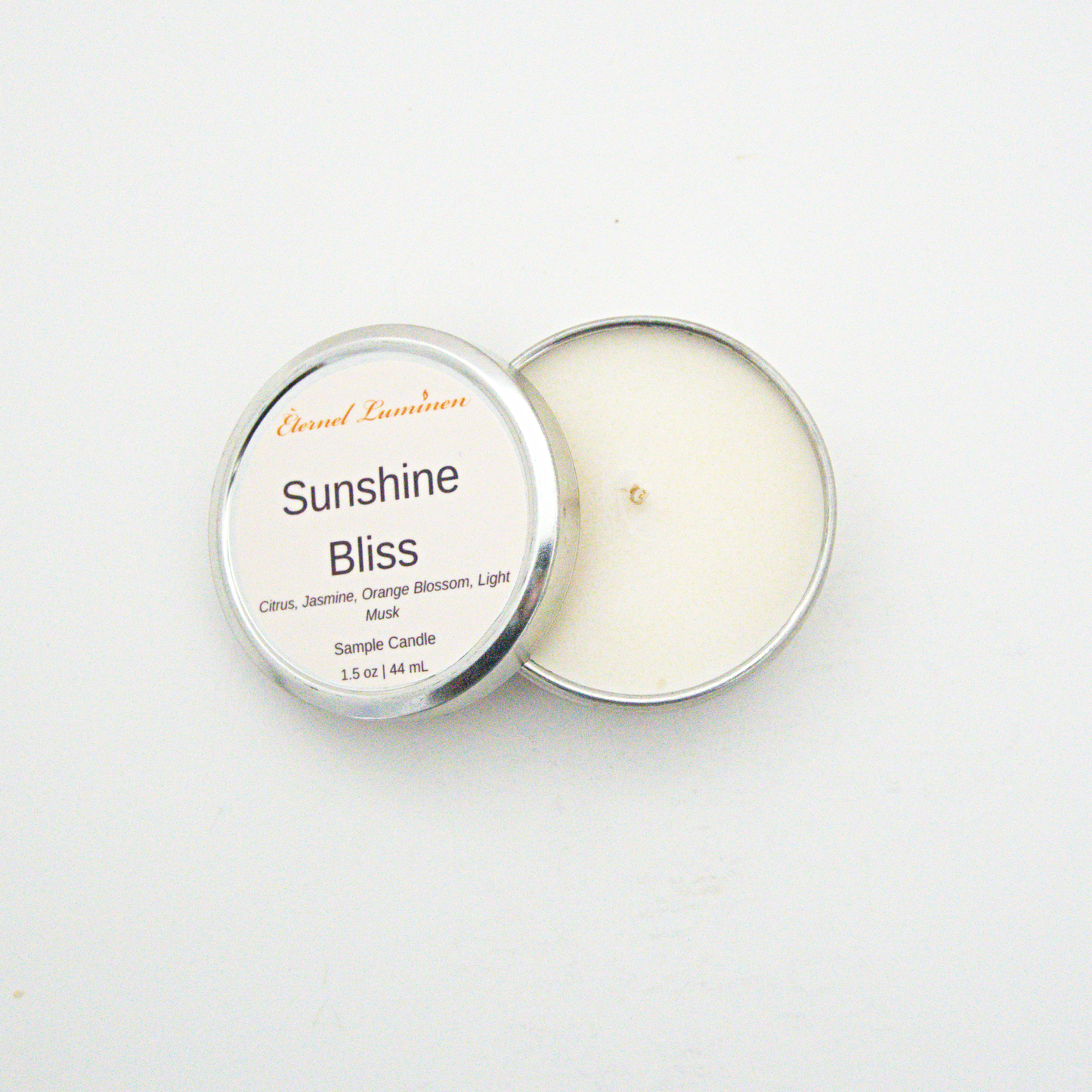 A 1.5oz Sunshine Bliss sample candle in a tin jar with the lid off sitting against a white background made by Eternel Luminen.