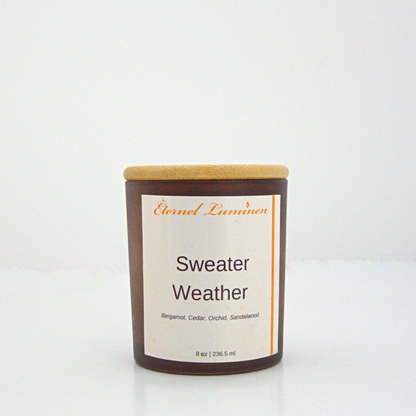 A 8 oz frosted Sweater Weather candle with a wooden lid sitting against a white background made by Eternel Luminen.