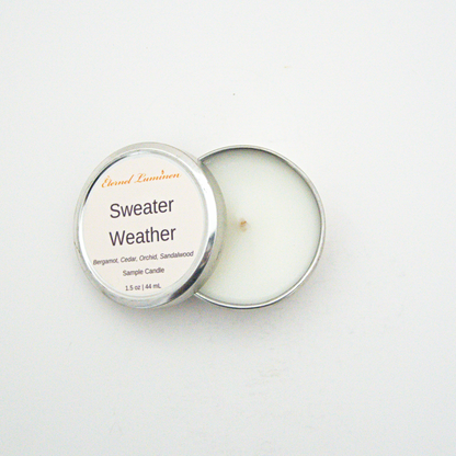 A 1.5oz Sweater Weather sample candle in a tin jar with the lid off sitting against a white background made by Eternel Luminen.