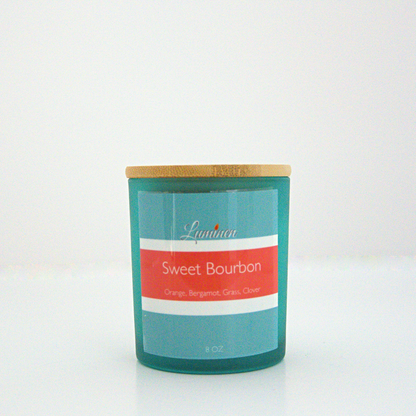 A 8 oz frosted Sweet Bourbon candle with a wooden lid sitting against a white background made by Eternel Luminen.