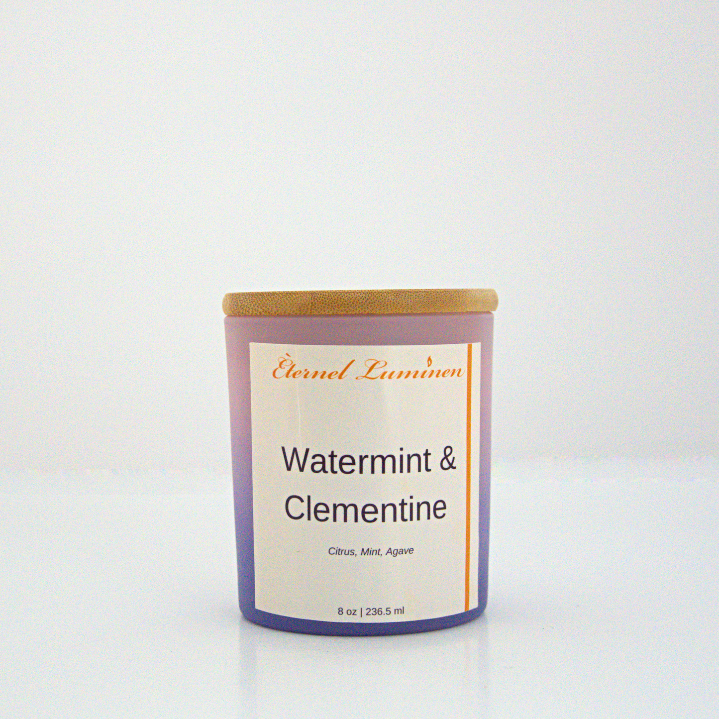 A 8 oz frosted Watermint & Clementine candle with a wooden lid sitting against a white background made by Eternel Luminen.