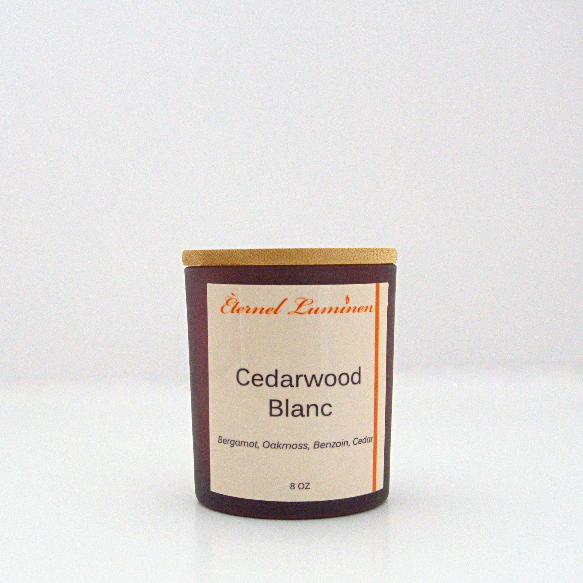 A 8oz frosted Cedarwood Blanc candle with a wooden lid sitting against a white background made by Eternel Luminen.