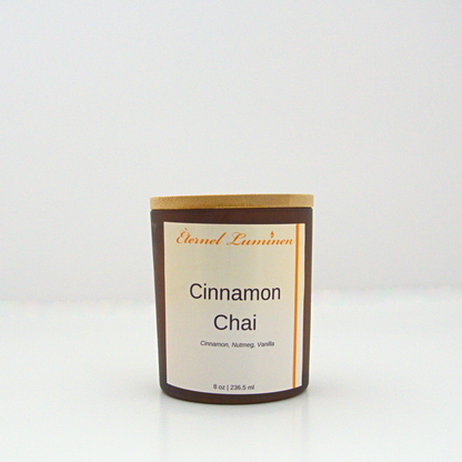 A 8 oz frosted Cinnamon Chai candle with a wooden lid sitting against a white background made by Eternel Luminen.