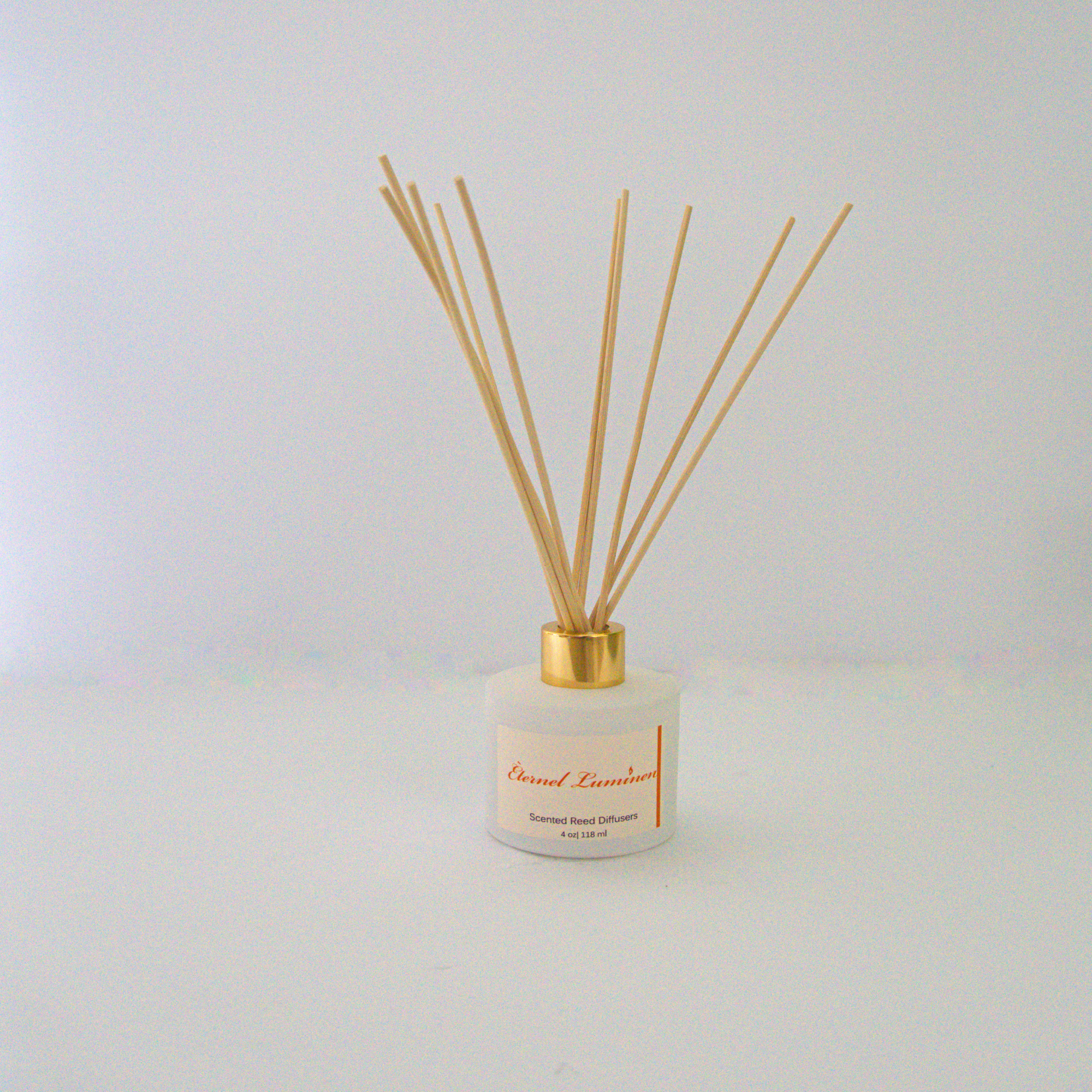 A 2.75 oz white jar with a gold band reed diffuser sitting against a white background made by Eternel Luminen.